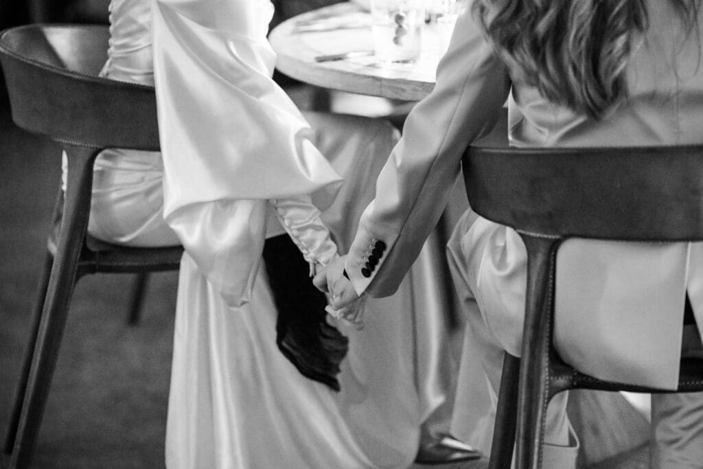 black & white photo of brides holding hands at Wild Flower Farms wedding in Gardiner NY